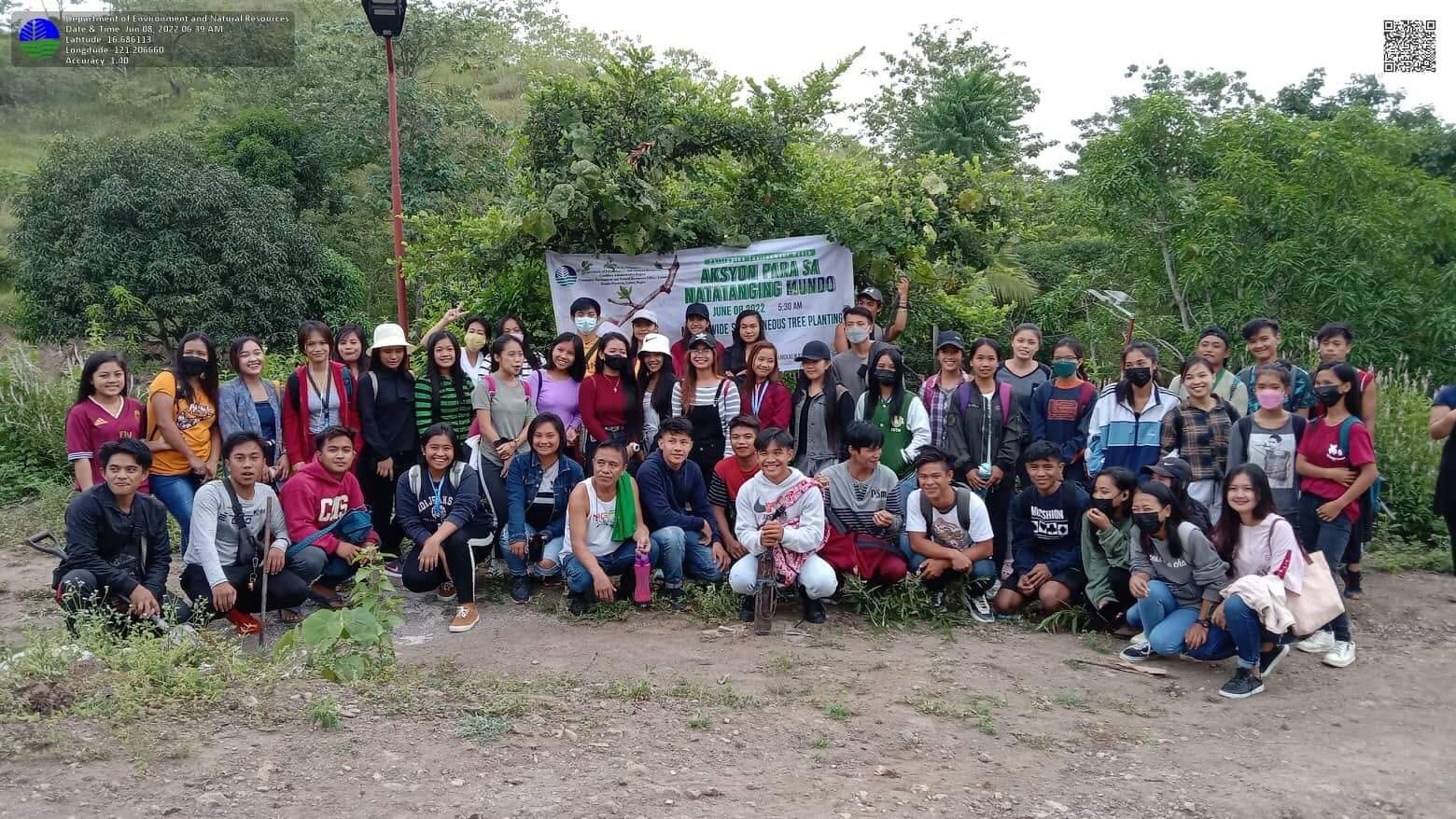 Participants gathered for a group photograph in front of a tree planting banner at a DENR field activity